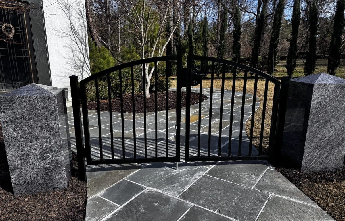 Black ornamental arched gate with granite pillars in Georgia