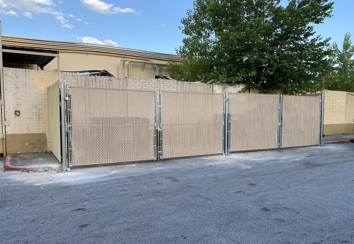 Large commercial chain link dumpster enclosure with privacy slats in Georgia