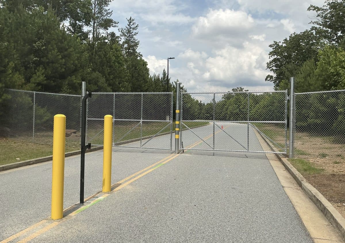 Chain link swing gate with yellow bollards at commercial property in Georgia