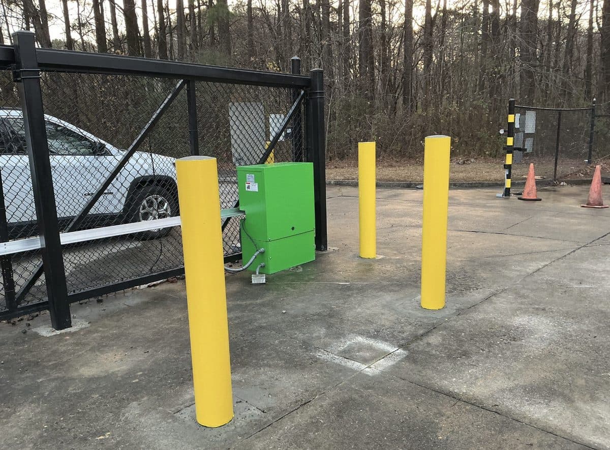 Yellow steel bollard installation at commercial security gate in Georgia